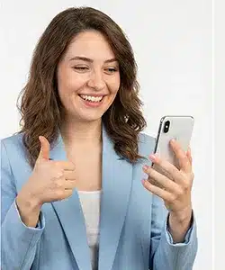 Telefonla görüntülü konuşurken başparmağını kaldırarak memnuniyet gösteren gülümseyen kadın.